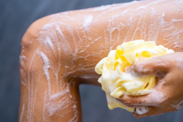 Mulher se ensaboando dentro da banheira com sabonete corporal 